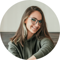 young adult female with long blonde hair smiling with black glasses frame and white side frame