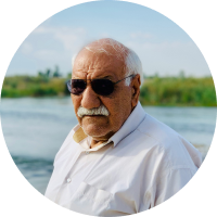 older European elder outside near lake with aviator sunglasses shades