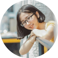 Asian girl with short hair leaning against a rail with black rectangular glasses frames